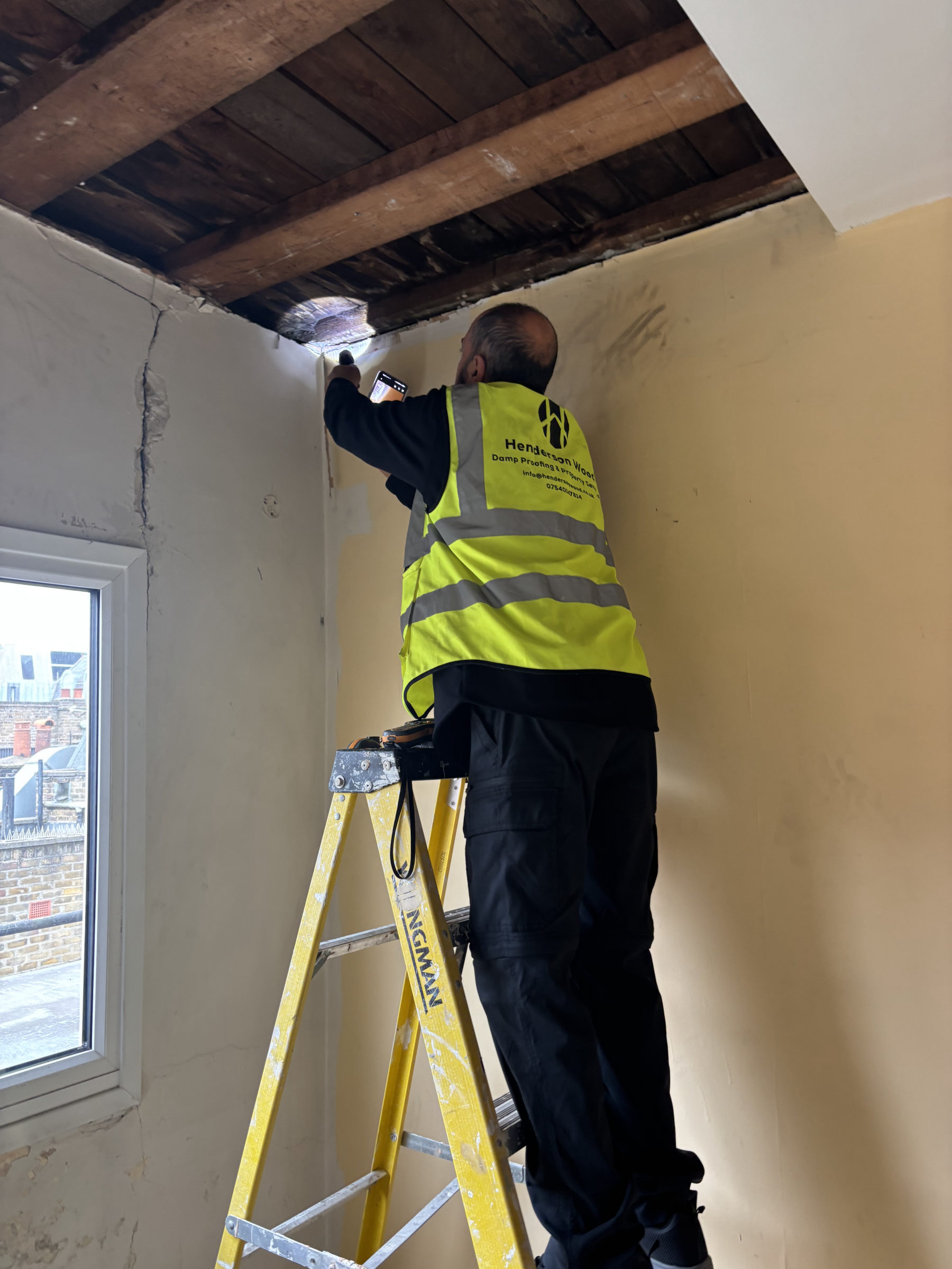Henderson Wood surveyor investigating a damp ceiling and wall during a condensation and mould survey