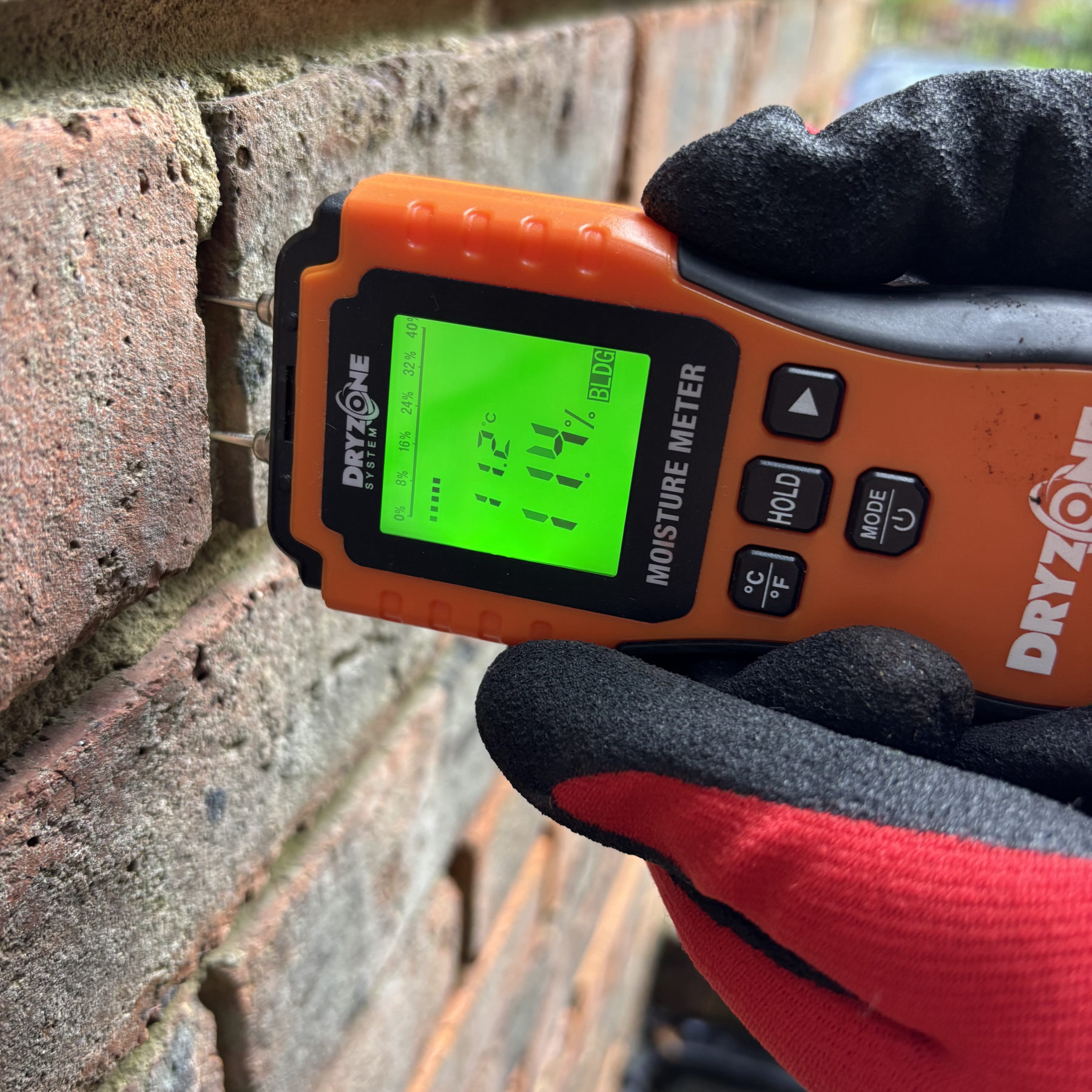 Henderson Wood surveyor taking moisture meter readings on a brick wall during a residential damp survey